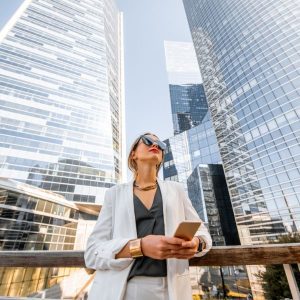 Businesswoman using a mobile phone near a business hub, representing current business trends.