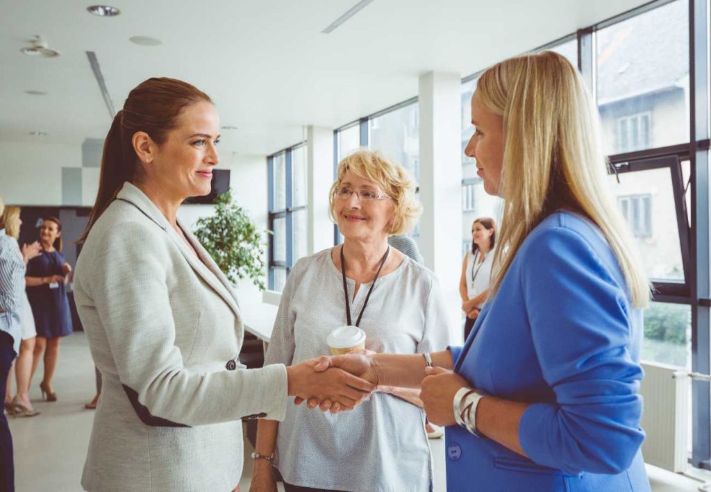 Two businesswomen shaking hands, representing global business solutions and partnerships.