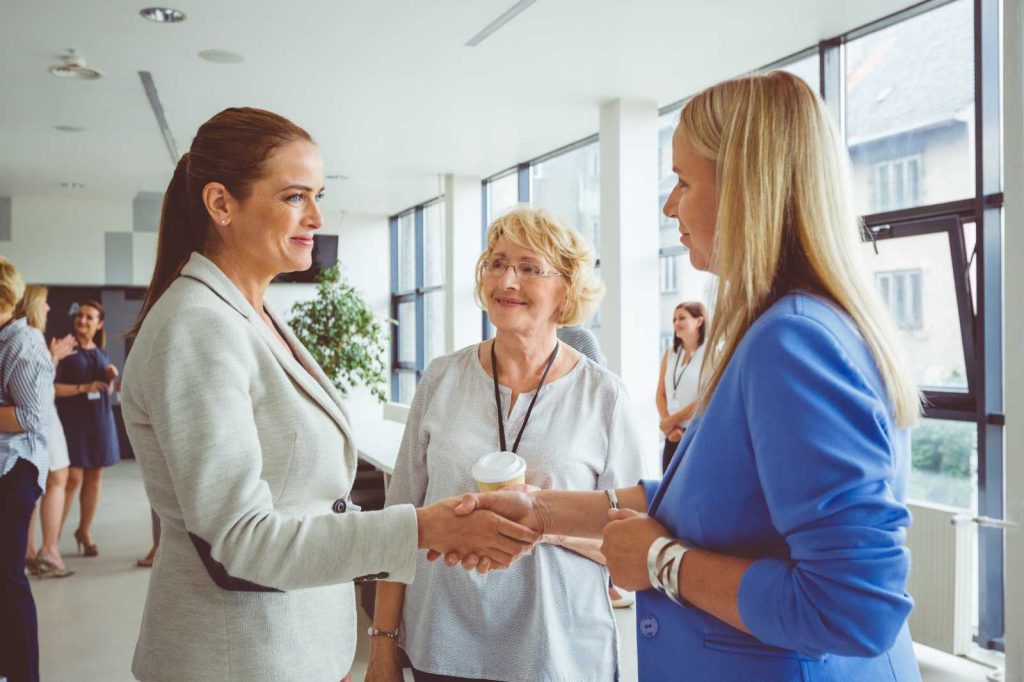 Two businesswomen shaking hands symbolizing global business support.